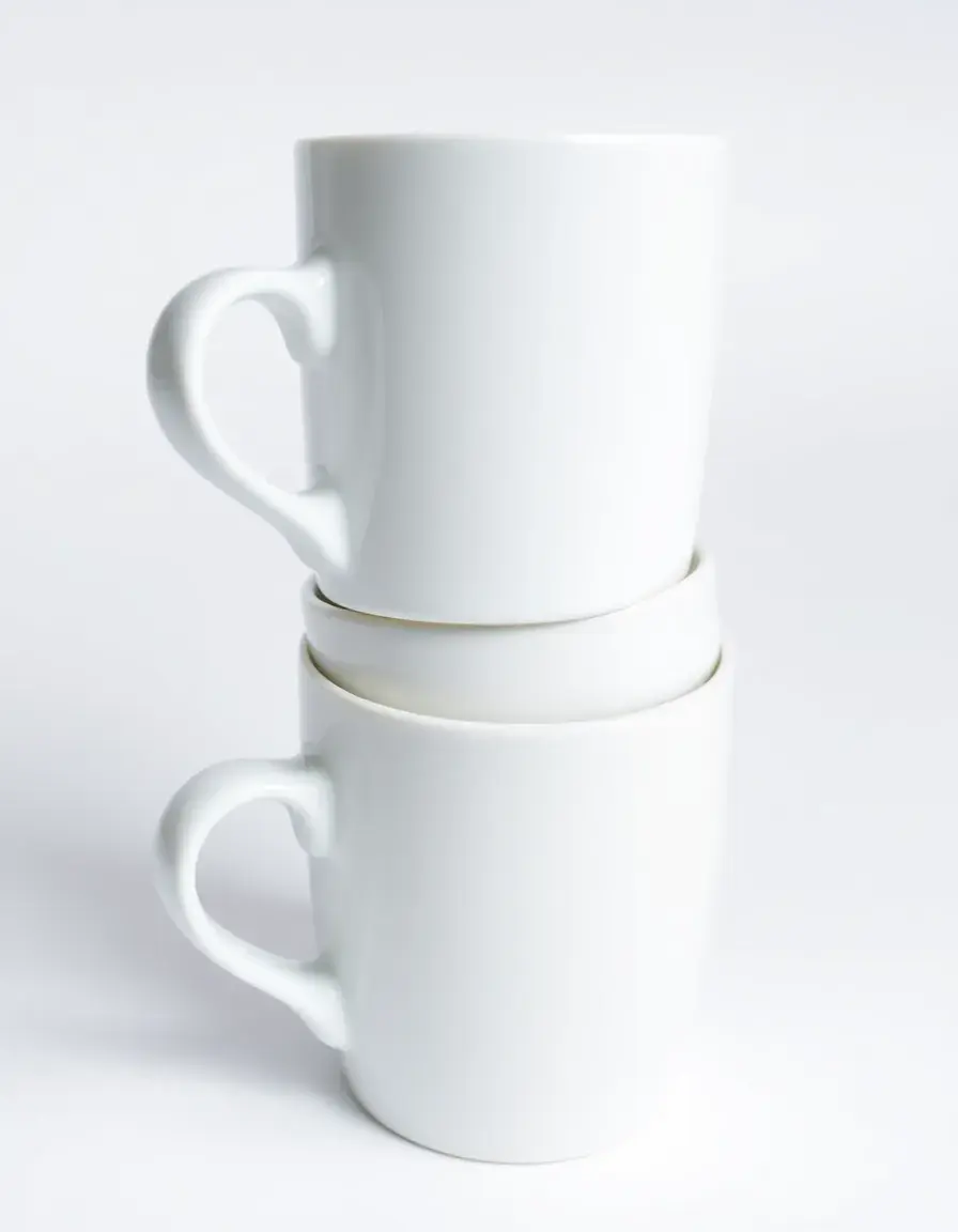 Set di 4 tazze in ceramica bianca impilate su sfondo chiaro